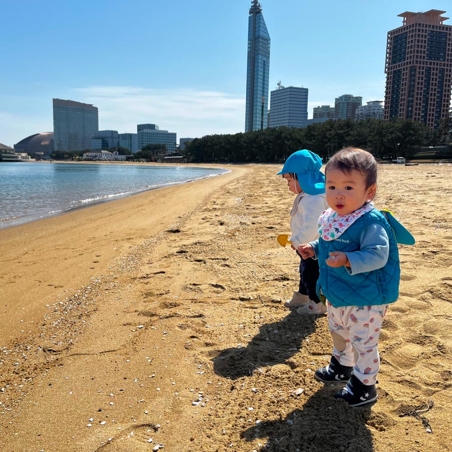 お散歩で百道浜の砂浜で遊ぶ子どもの写真