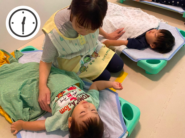 保育士に寝かしつけをしてもらい安心して眠る赤ちゃんの写真