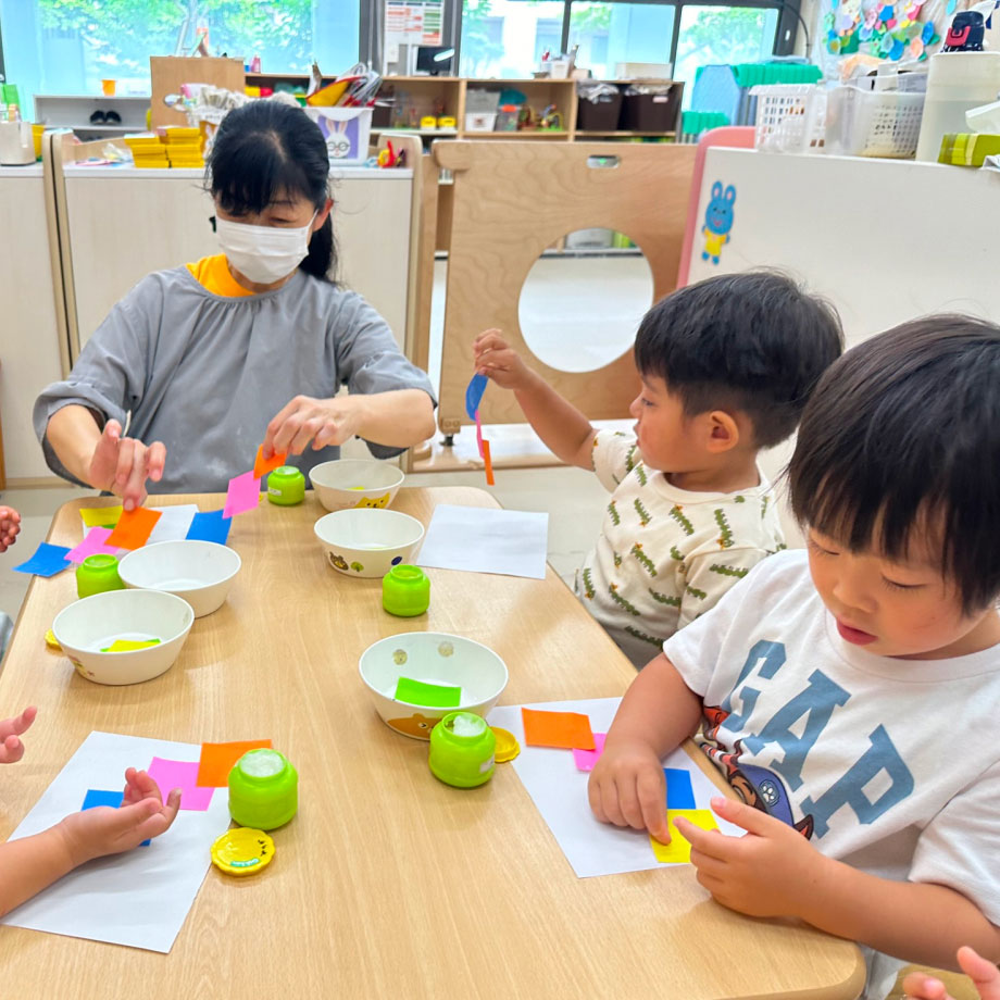 指先を使い、折り紙にのりを塗る様子の写真