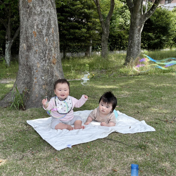 お散歩で外に出て自然の中で過ごす0歳児の写真