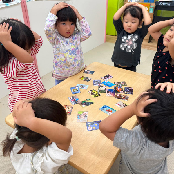 みんなでルールを守ってカルタで遊ぶ園児の写真